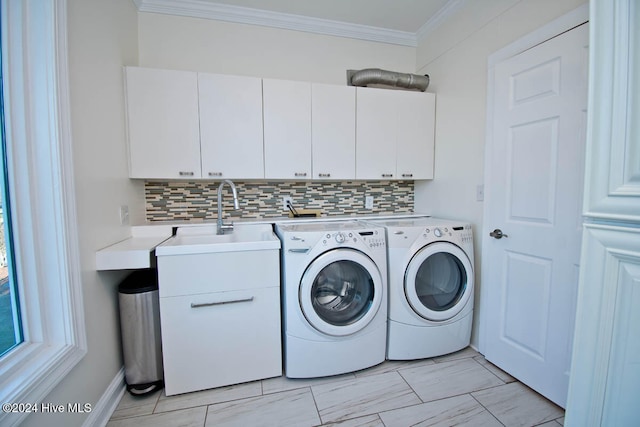 clothes washing area with crown molding, washer and dryer, sink, and cabinets