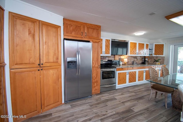 105 Wind Dance Ln, Swansboro, NC 28584 - kitchen with appliances with stainless steel finishes, decorative backsplash, light wood finished floors, open shelves, and brown cabinetry