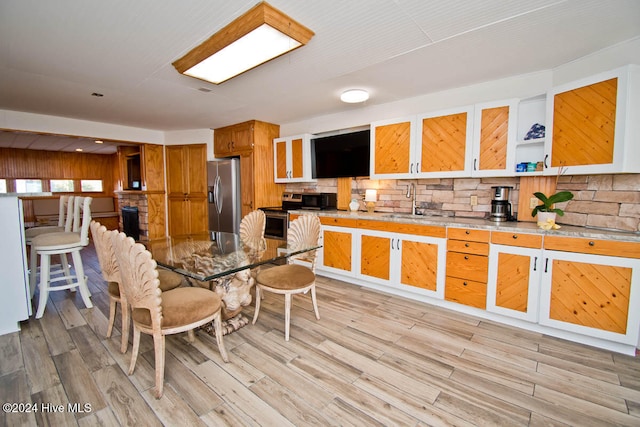 kitchen with decorative backsplash, stainless steel appliances, light hardwood / wood-style floors, and sink