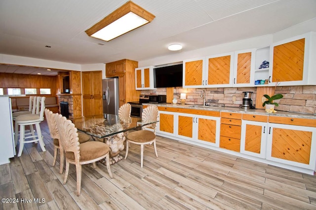 105 Wind Dance Ln, Swansboro, NC 28584 - kitchen featuring appliances with stainless steel finishes, backsplash, a sink, brown cabinets, and light wood finished floors