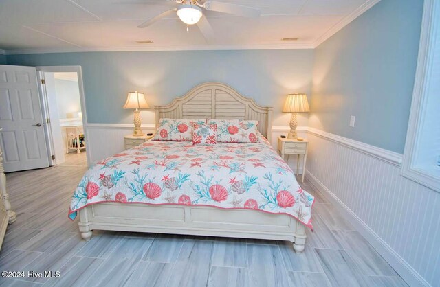105 Wind Dance Ln, Swansboro, NC 28584 - bedroom with a wainscoted wall, ornamental molding, light wood-style flooring, and ceiling fan