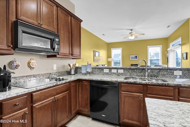 kitchen with light tile patterned flooring, a sink, a ceiling fan, light stone countertops, and black appliances