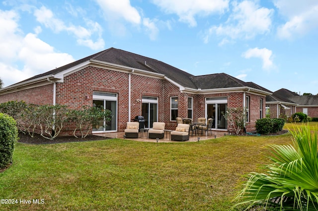 rear view of property featuring a yard, a patio, and brick siding