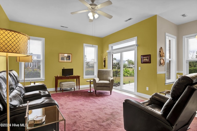 living area with carpet floors, visible vents, and ceiling fan