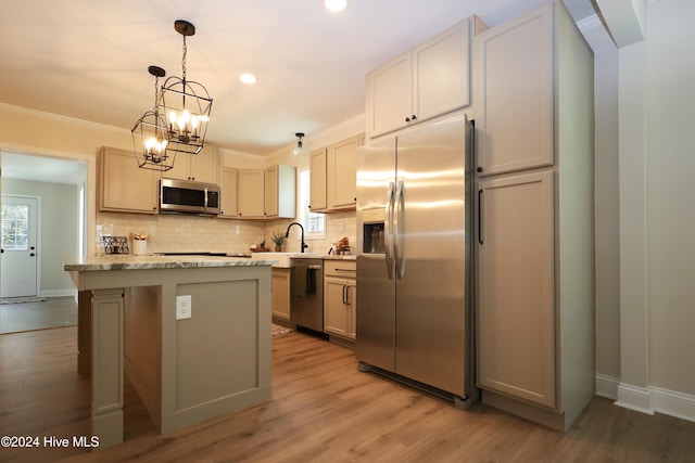 kitchen featuring ornamental molding, stainless steel appliances, a center island, light hardwood / wood-style floors, and hanging light fixtures