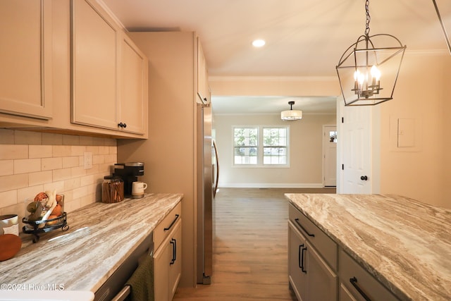 kitchen with light stone countertops, ornamental molding, dark hardwood / wood-style floors, stainless steel refrigerator, and hanging light fixtures