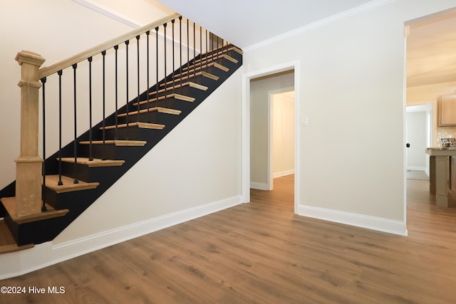 stairs with crown molding and hardwood / wood-style flooring