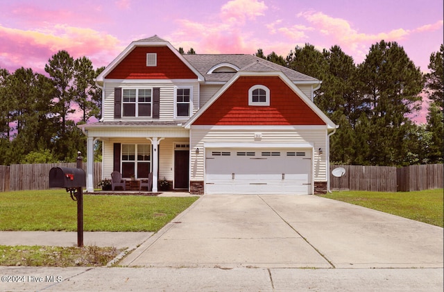 view of front of house with a yard, covered porch, and a garage