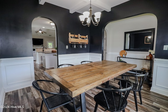 dining space featuring sink, dark hardwood / wood-style flooring, ceiling fan with notable chandelier, and beam ceiling