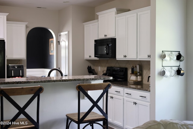 kitchen featuring black appliances, sink, dark stone countertops, tasteful backsplash, and white cabinetry