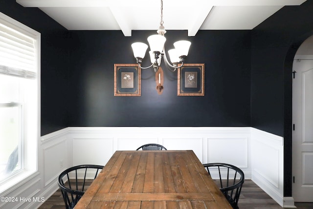 dining space featuring beamed ceiling, a notable chandelier, dark wood-type flooring, and a wealth of natural light