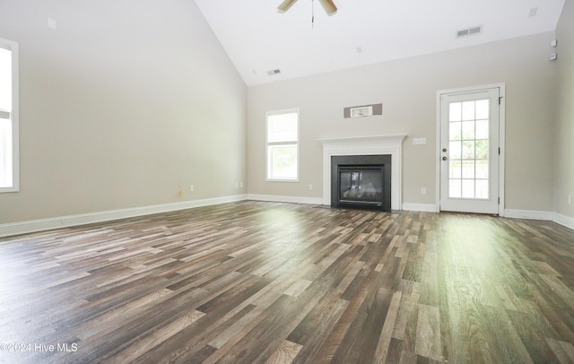 unfurnished living room featuring a wealth of natural light, high vaulted ceiling, and dark hardwood / wood-style floors