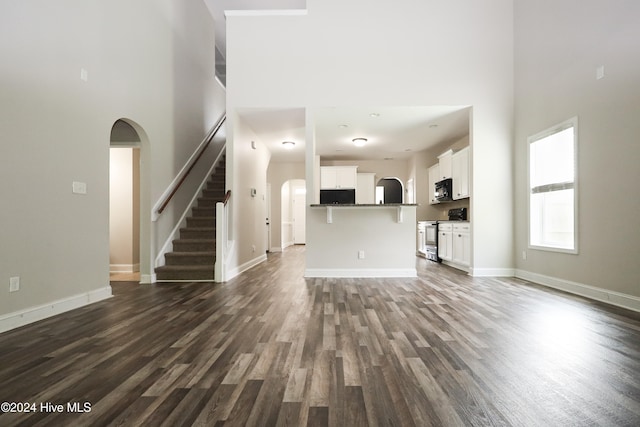 unfurnished living room with a high ceiling and dark hardwood / wood-style flooring