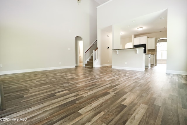 unfurnished living room featuring a towering ceiling and dark wood-type flooring