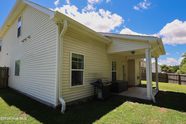 back of house with a lawn and a patio