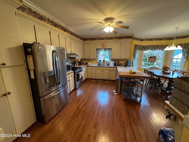 kitchen with stainless steel appliances, crown molding, cream cabinets, dark hardwood / wood-style floors, and hanging light fixtures