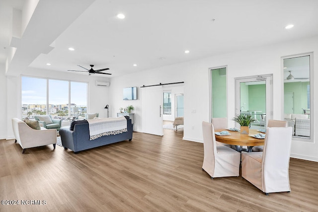 bedroom featuring a wall mounted air conditioner, ceiling fan, multiple windows, and light hardwood / wood-style flooring