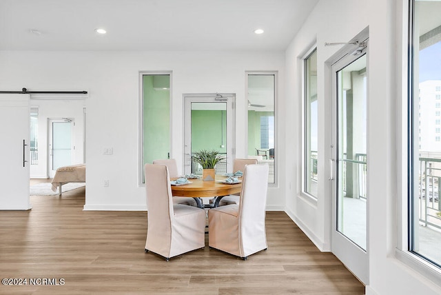 dining area featuring a healthy amount of sunlight, a barn door, and light wood-type flooring