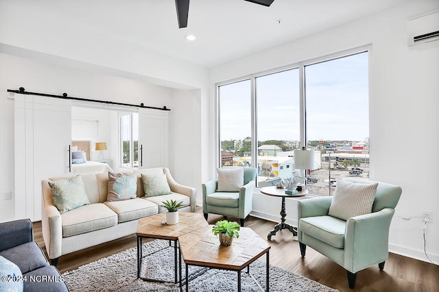 living room with a barn door, ceiling fan, dark wood-type flooring, and a wall mounted AC