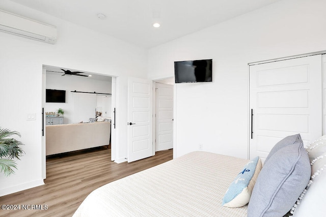 bedroom featuring a wall mounted AC, wood-type flooring, and vaulted ceiling