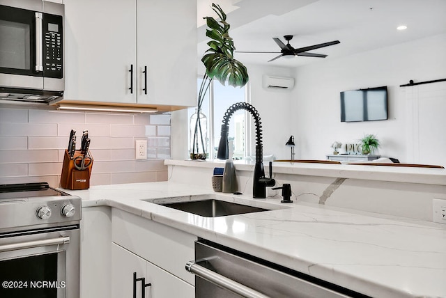 kitchen with sink, tasteful backsplash, a wall mounted AC, white cabinets, and appliances with stainless steel finishes