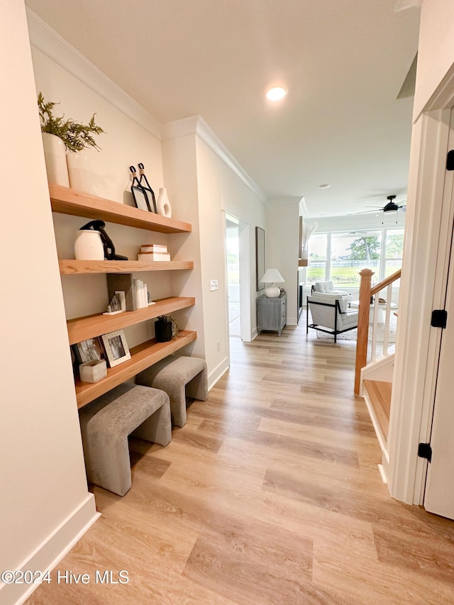 hall with stairs, baseboards, crown molding, and light wood finished floors