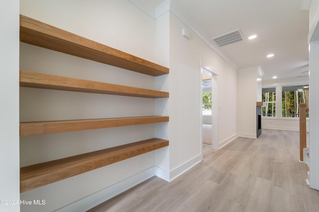 corridor with crown molding, baseboards, visible vents, and light wood finished floors