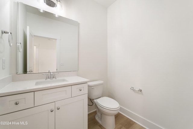 bathroom with baseboards, toilet, wood finished floors, and vanity