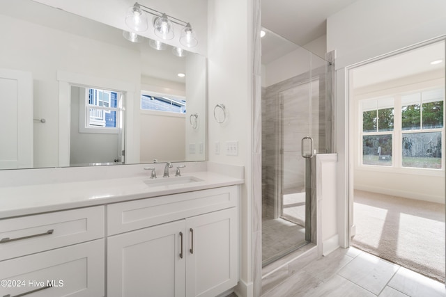 bathroom featuring plenty of natural light, a shower with door, and vanity