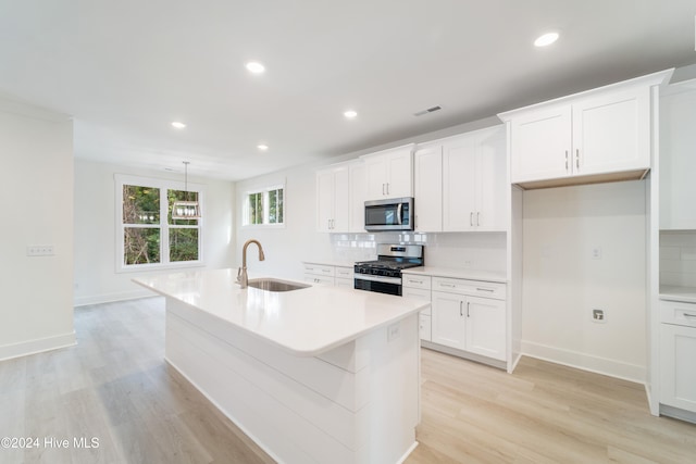 kitchen featuring white cabinetry, appliances with stainless steel finishes, sink, and a center island with sink