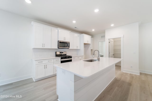 kitchen featuring sink, white cabinetry, a center island with sink, appliances with stainless steel finishes, and light hardwood / wood-style floors