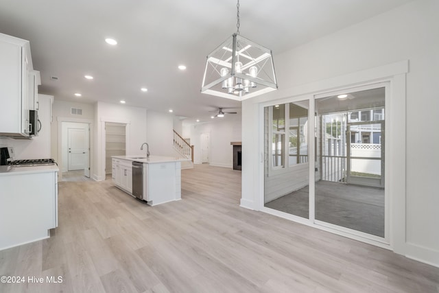 kitchen with sink, appliances with stainless steel finishes, an island with sink, pendant lighting, and white cabinets