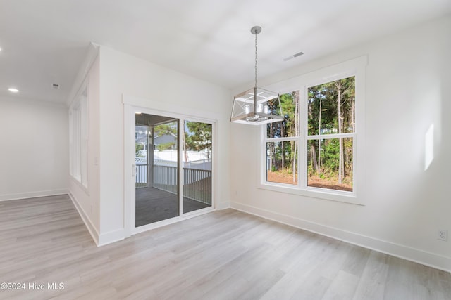 unfurnished dining area featuring a chandelier, visible vents, light wood finished floors, and baseboards