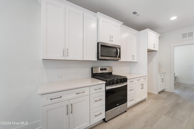 kitchen featuring visible vents, light wood finished floors, white cabinets, appliances with stainless steel finishes, and backsplash