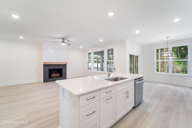 kitchen with stainless steel dishwasher, an island with sink, a healthy amount of sunlight, and a sink