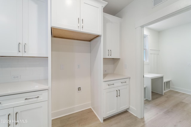 kitchen featuring backsplash, light wood-style floors, light countertops, and white cabinetry