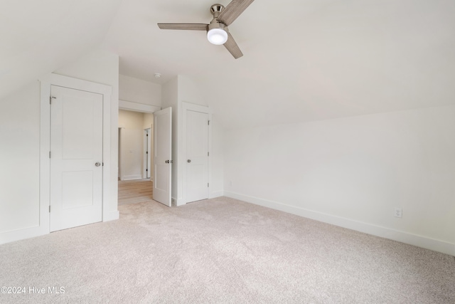 interior space featuring vaulted ceiling, light colored carpet, and ceiling fan