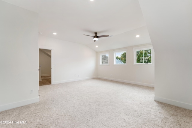 spare room featuring vaulted ceiling, light colored carpet, and ceiling fan