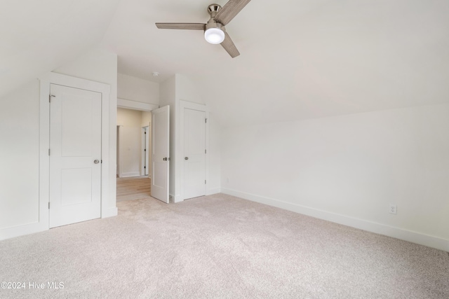 interior space featuring ceiling fan, lofted ceiling, baseboards, and light carpet