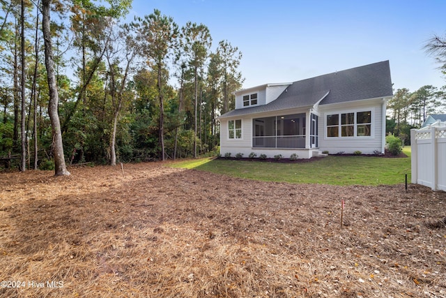 back of property with a yard, a sunroom, and roof with shingles