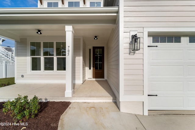 doorway to property with covered porch and a garage