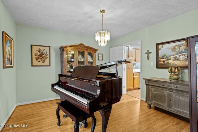 misc room with a chandelier, light hardwood / wood-style floors, and a textured ceiling