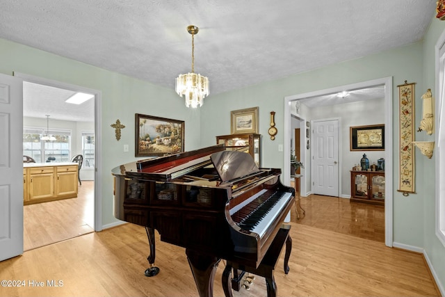 miscellaneous room featuring light hardwood / wood-style floors, a textured ceiling, and a notable chandelier