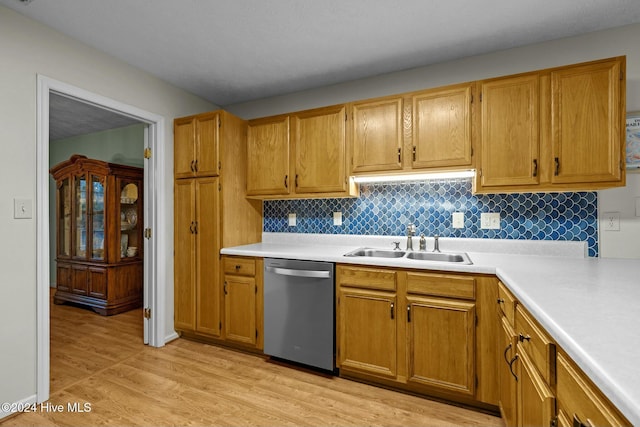 kitchen with backsplash, dishwasher, sink, and light hardwood / wood-style flooring