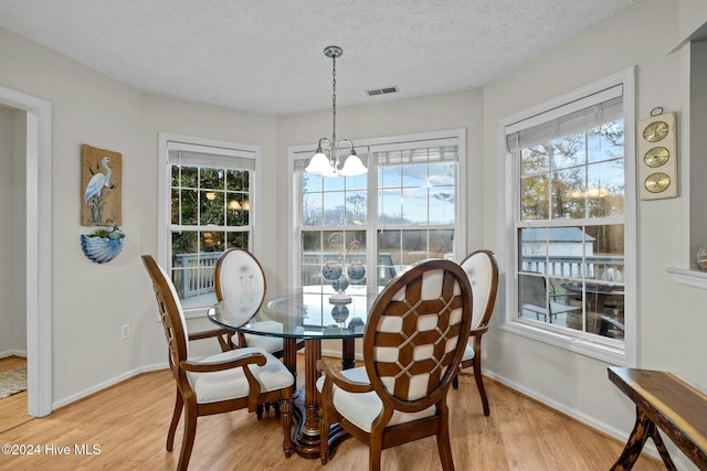 dining room featuring an inviting chandelier, a textured ceiling, and light hardwood / wood-style flooring