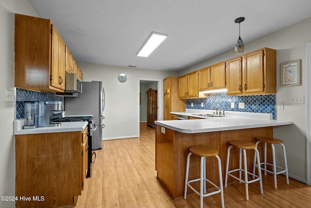 kitchen featuring kitchen peninsula, decorative backsplash, sink, light hardwood / wood-style flooring, and hanging light fixtures