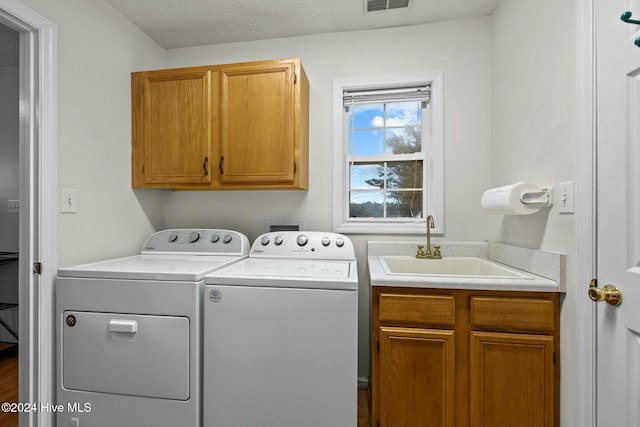 washroom featuring a textured ceiling, cabinets, independent washer and dryer, and sink