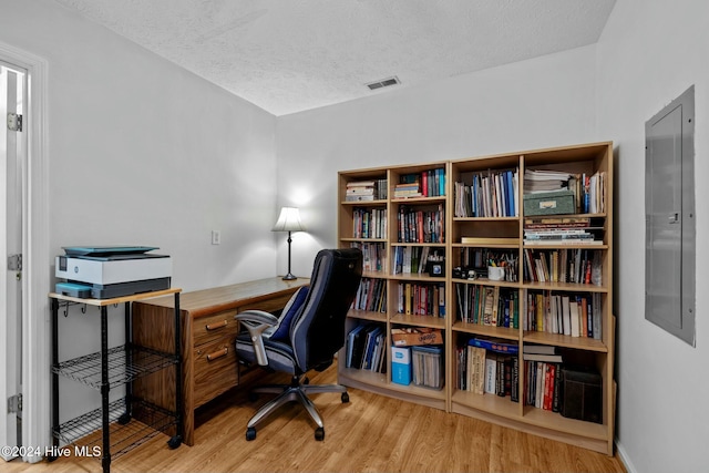 home office featuring electric panel, hardwood / wood-style floors, and a textured ceiling