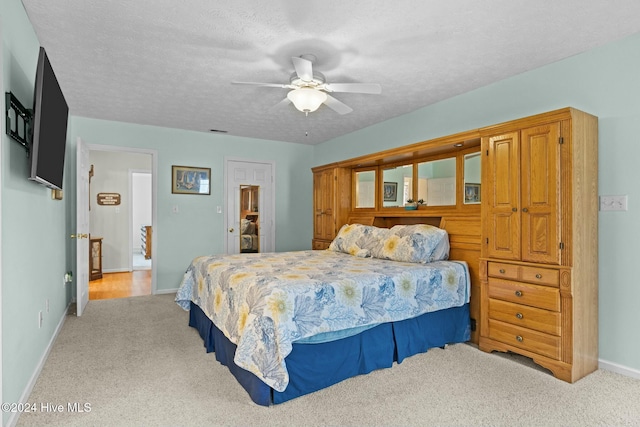 bedroom with a textured ceiling, ceiling fan, and light carpet