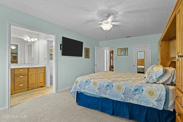 bedroom featuring ensuite bathroom, ceiling fan, light colored carpet, and a textured ceiling